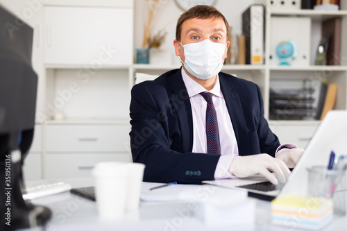 Entrepreneur in medical mask and gloves working in office