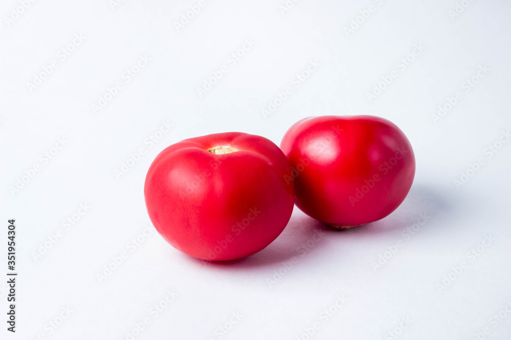 two red tomatoes on a white background.
