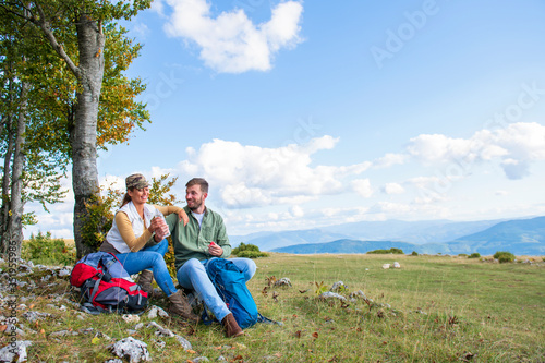 Young couple drinking water while resting on the rock during the travel in the mountains © FS-Stock