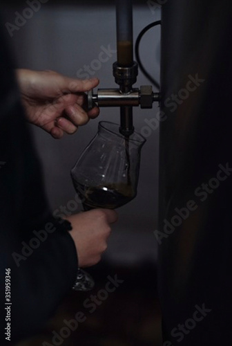 brewer pours freshly brewed beer into a glass