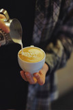 barista pours milk into a cappuccino