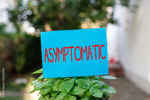 Writing note showing Asymptomatic. Business concept for a condition or an individual producing or showing no symptoms Plain paper attached to stick and placed in the grassy land photo