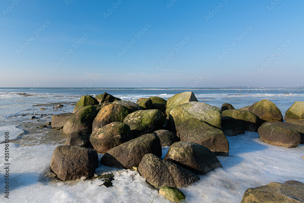 Green and brown boulders in an icy winter landscape with a blue sky a wonderful crispy cold winterday