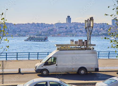 Foto A van with mobile communications network antennas parked in front of the Bosphorus with Istanbul skyline in the background