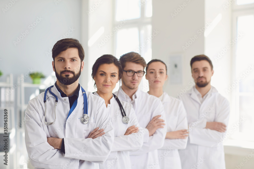 A group of confident practicing doctors cross arms in white coats are smiling in the clinic. A group of confident practicing doctors cross arms in white coats are smiling in the clinic.