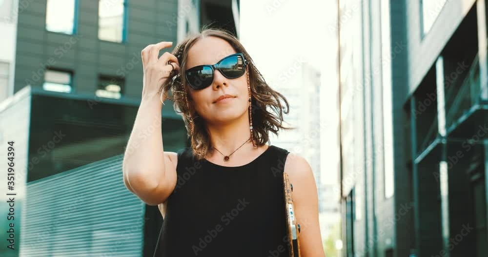 Stylish girl portrait looking in camera. She wears sunglasses, wind blows hair. Stylish girl portrait looking in camera. She wears sunglasses, wind blows hair.