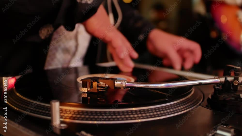 A close-up of the hand of a man who plays on a vinyl record. DJ at work at a party or concert at night. A close-up of the hand of a man who plays on a vinyl record. DJ at work at a party or concert at night.
