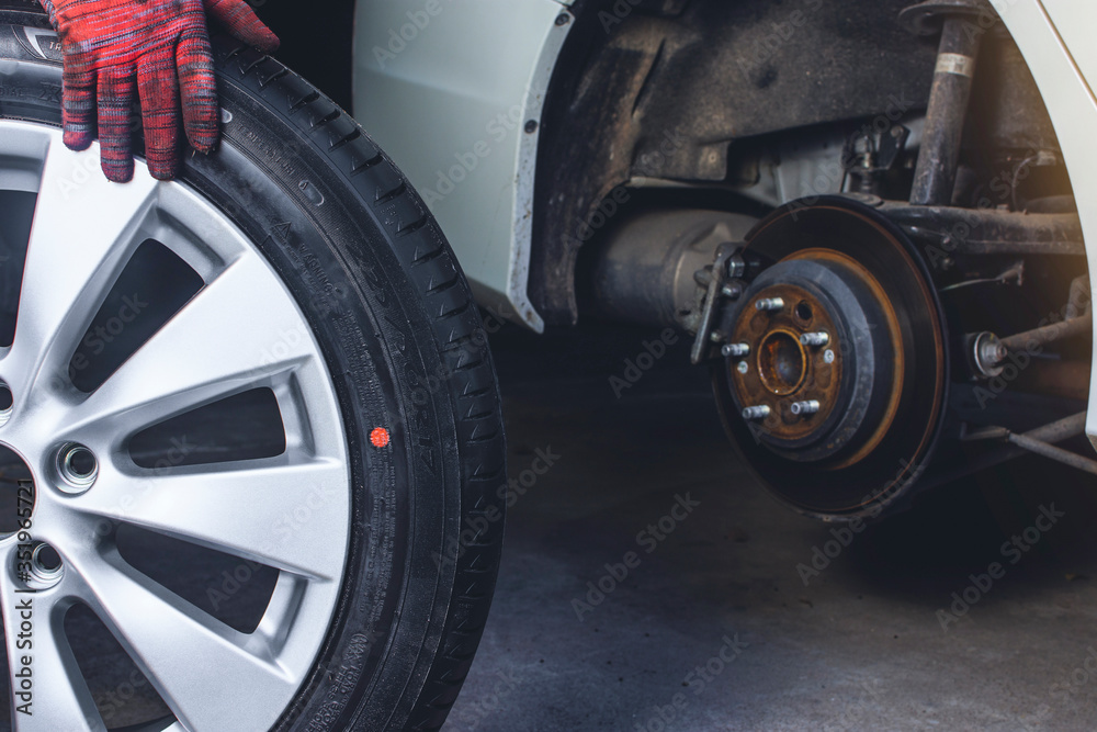 Car mechanic pushes the alloy wheels to install into the wheel hub in vehicle repair shop. Car mechanic pushes the alloy wheels to install into the wheel hub in vehicle repair shop.