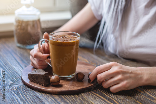 Woman is holding a transparent glass with delicious and refreshing whipped coffee. A trendy spectacular drink that can made at home
