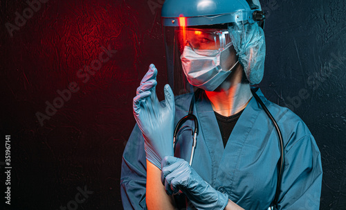 female doctor with a stethoscope on her neck, in a medical mask and glasses on her face on a dark background