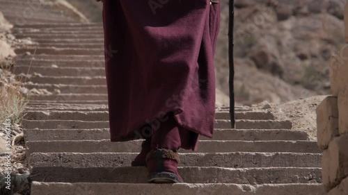 A lone Tibetan pilgrim in national dress turns prayer wheels at the foot of the temple