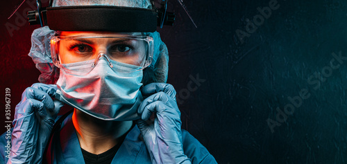 female doctor with a stethoscope on her neck, in a medical mask and glasses on her face on a dark background © Mikhaylovskiy 