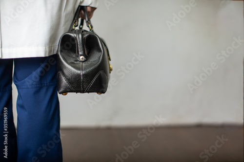 Female physician holding a black leather doctor's bag heading to the office to practice medicine photo