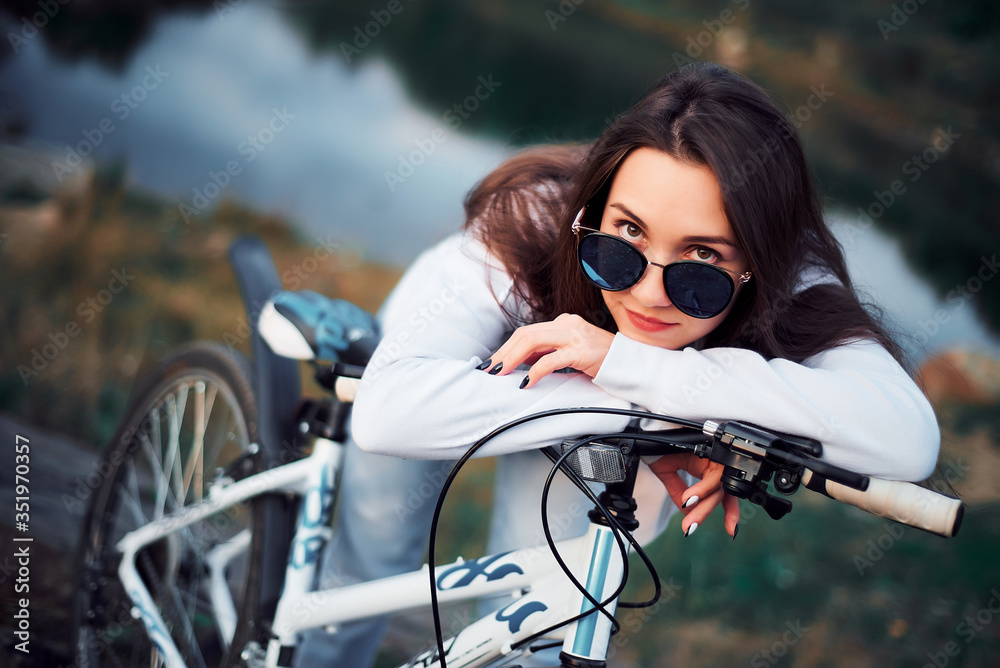 Naklejka premium Girl in the mountains on a Bicycle on the background of a lake, close-up portrait, resting, healthy lifestyle, Cycling, nature and man