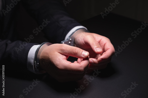 Handcuffed hands in a dark room