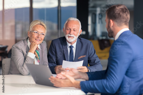 Fotografie Positive aged couple consulting with insurance agent