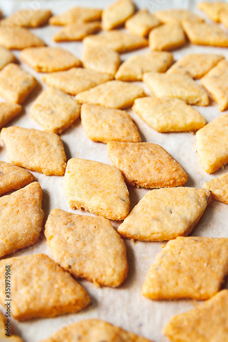 Freshly baked cheese cookies. Closeup of a lot of hot fresh pastry on a baking sheet. Selective soft focus.