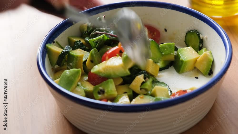 Mixing salad with avocado, tomato, cucumber and green salad leaves tossed with olive oil. Healthy vegan, vegetarian salad bowl Mixing salad with avocado, tomato, cucumber and green salad leaves tossed with olive oil. Healthy vegan, vegetarian salad bowl