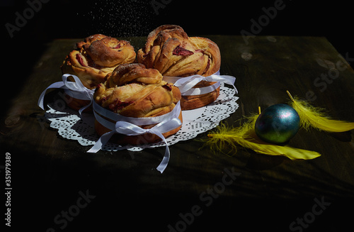 side view of kraffins on a white napkin with feathers and an egg on a wooden background photo