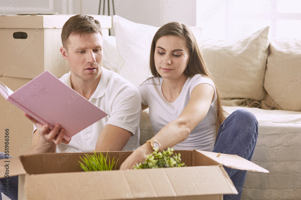 Portrait of happy couple looking at laptop computer together sitting in new house, surrounded with boxes Portrait of happy couple looking at laptop computer together sitting in new house, surrounded with boxes
