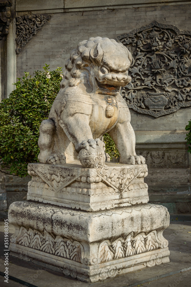 A Chinese white lion stands on the landing in front of the temple entrance.