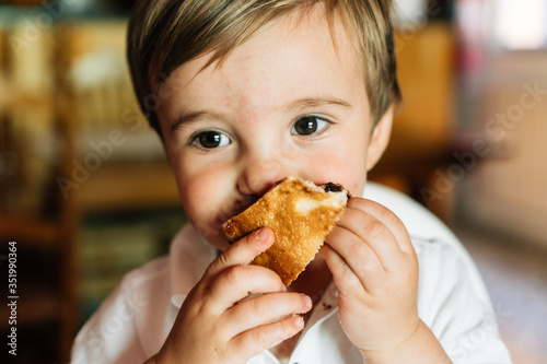 little boy with blond hair eats a chocolate cake.