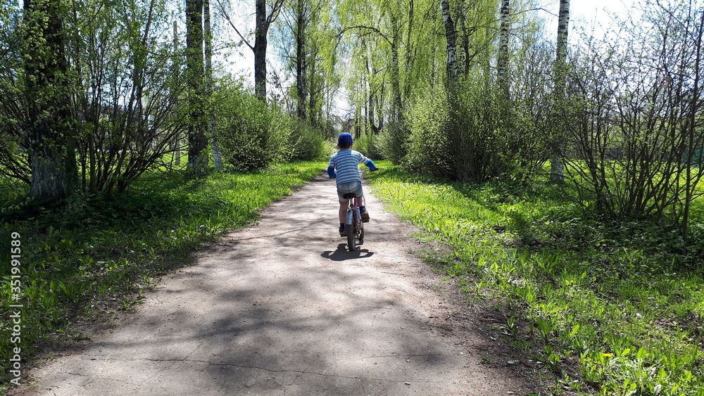 Young boy riding strider bike. the first spring foliage