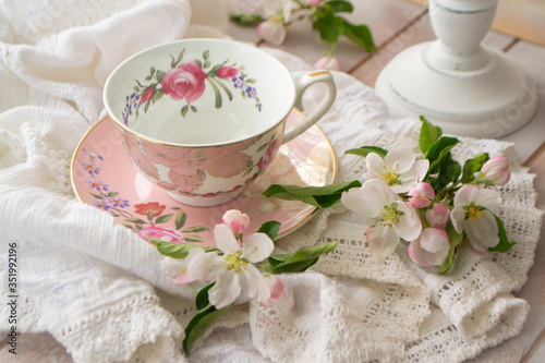 Pretty pink vintage afternoon tea party, tea cup and tender flowers on wooden tray and lace tablecloth