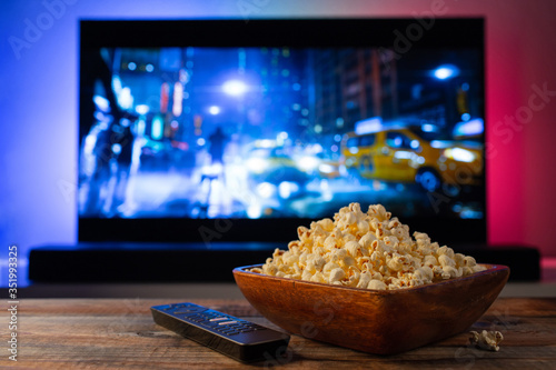Foto A wooden bowl of popcorn and remote control in the background the TV works