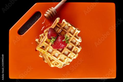 Viennese waffles with strawberries topping with honey