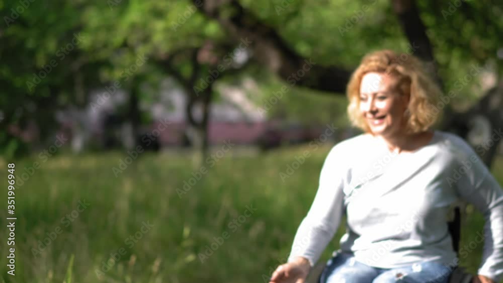 Mother in a wheel chair playing frisbee with kids outdoor in the park or backyard. Mother throwing a frisbee to her kids and they bring it back to her running happy. Mother in a wheel chair playing frisbee with kids outdoor in the park or backyard. Mother throwing a frisbee to her kids and they bring it back to her running happy.