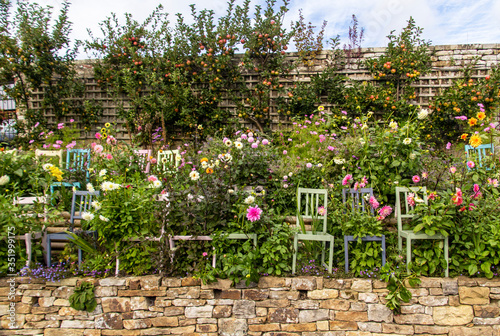 Beautiful garden floral arrangement incorporating brightly coloured chairs  landscape view