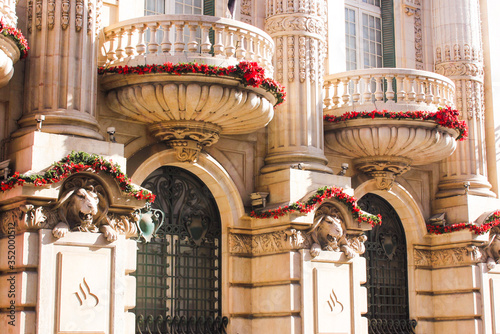 Totta Banco Santander building in Portugal, Lisbon, with decorative elements: semicircular balconies solemnly decorated with red flowers, sculptures of lion heads.