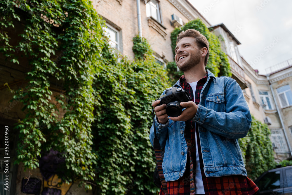 Fototapeta premium Photographer, freelancer. Stylish hipster man in casual clothing walking alone with his camera, leisure and creative relax. Hobby