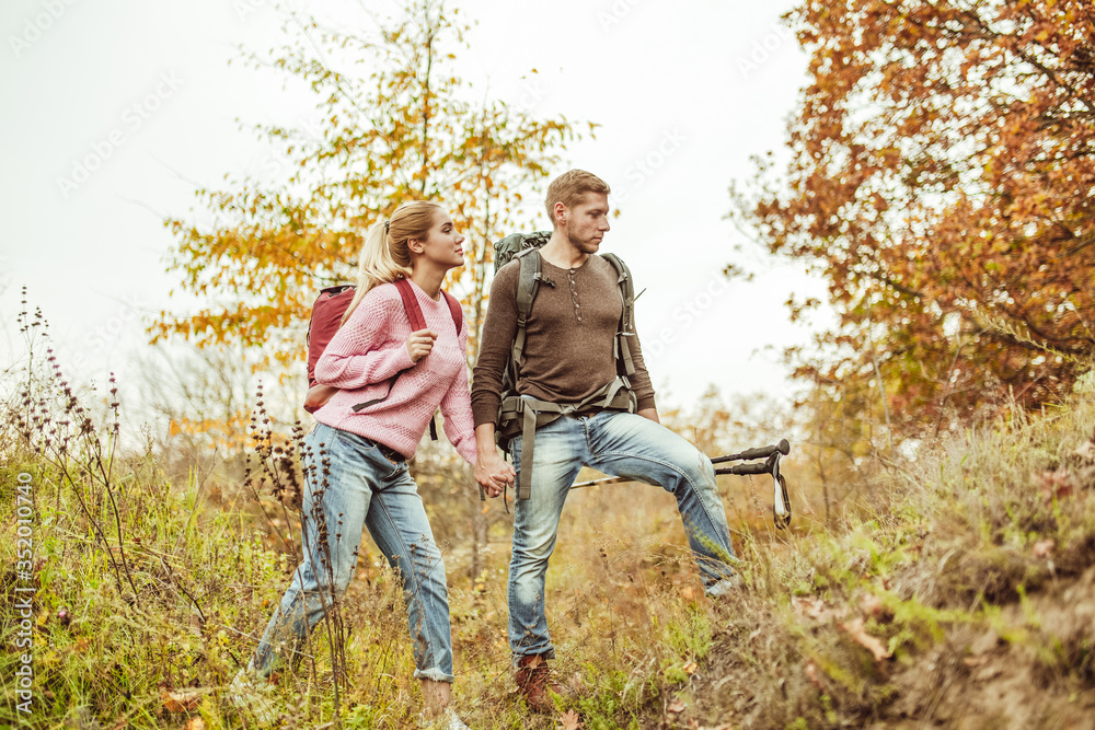 Tourists wading through the hills holding hands. A young couple of people in love checks the strength of their relationship while traveling in the wild. Hiking concept Tourists wading through the hills holding hands. A young couple of people in love checks the strength of their relationship while traveling in the wild. Hiking concept