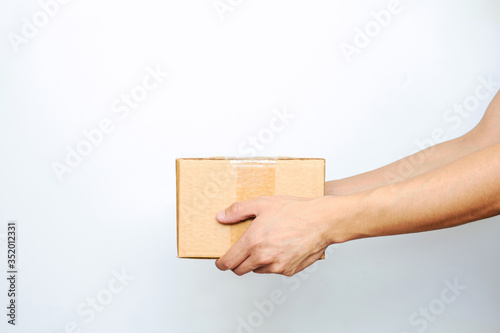 Hands hold a cardboard box for online grocery and food delivery on a white isolated background with copy space. The concept of courier business of buying and ordering