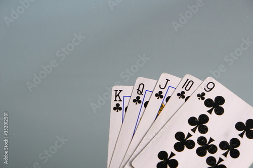 Club Straight Flush Playing Cards. Five card hands. Nine, Ten, jack, queen, king on blue grey background. Poker hand and card games. Club suit almost a royal flush, gambling. Las Vegas
