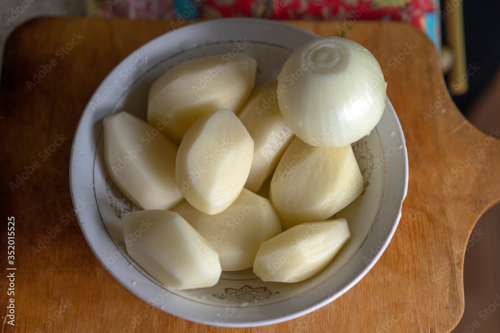 Peeled raw potatoes and onions Peeled raw potatoes and onions