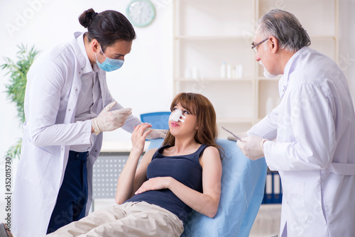 Two male doctors and young woman in plastic surgery concept