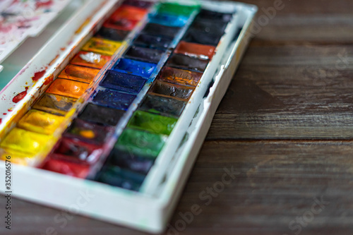 Set of watercolor paints and paintbrushes for painting closeup. Selective focus. wooden background. Copy space