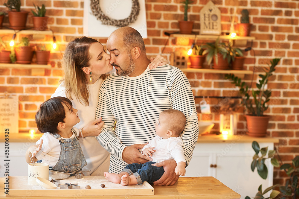 Fototapeta premium young beautiful family having fun and cooking in the sunny kitchen
