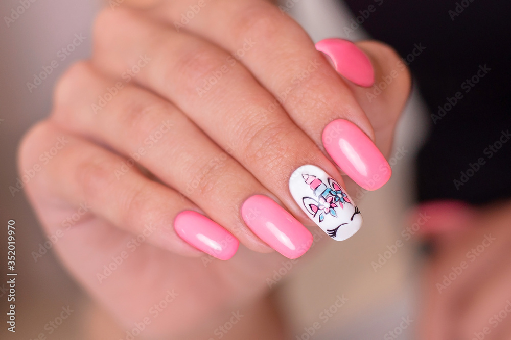 Female hands with creative pink manicure with unicorn design on nails