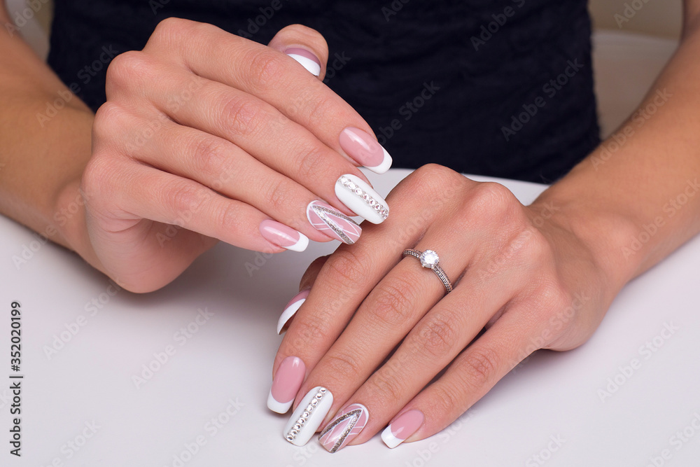 Female hands with stylish and luxury french manicure nails and ring on fingers. Wedding style. Female hands with stylish and luxury french manicure nails and ring on fingers. Wedding style.