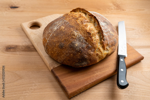 Homemade boule (round loaf) of freshly baked sourdough bread on a wood cutting board