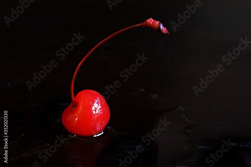 Isolated Maraschino cherry against a black background.
 photo