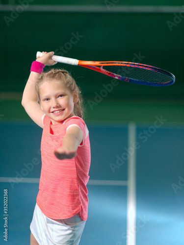 A girl plays tennis on an indoor tennis court. © sheikoevgeniya