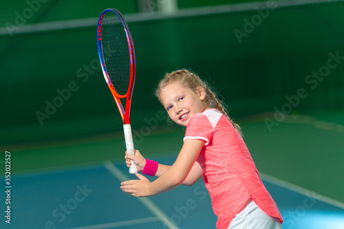 A girl plays tennis on an indoor tennis court.