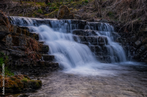 Waterfall Zalotomyatyi at the Zalotomyatyi river in carpatian mountains and green forest. National park Skolivski Beskidy. April 2020