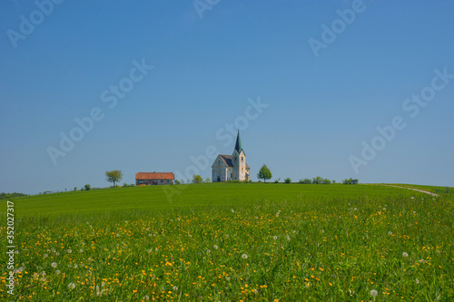 Slovenian countryside in spring with charming little church on a hill, in Slovenia