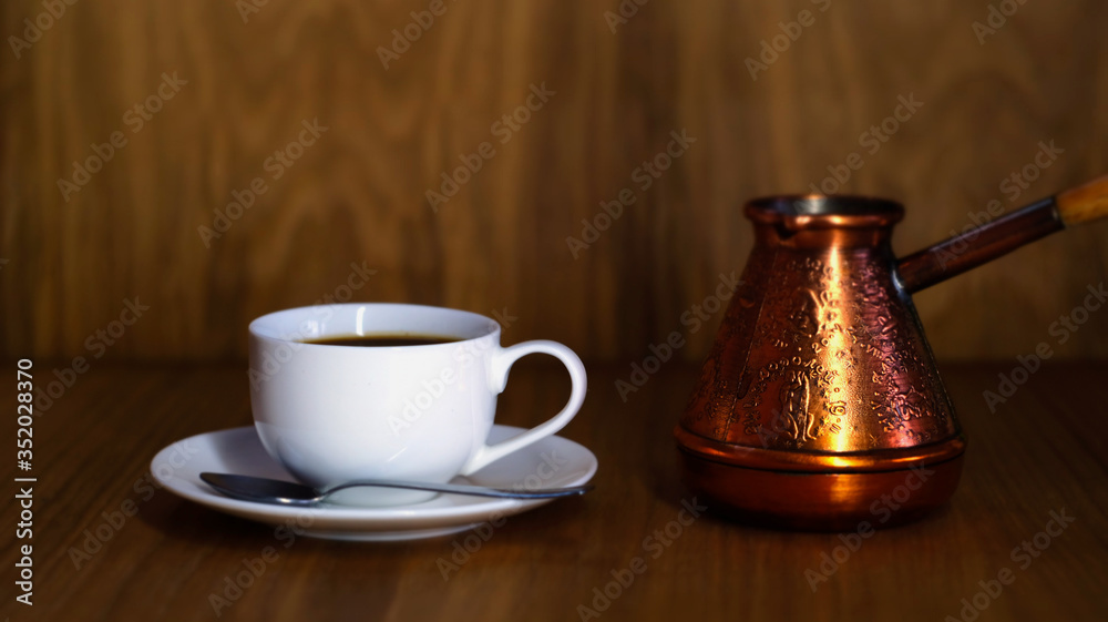 White cup with coffee, spoon, saucer and cezve